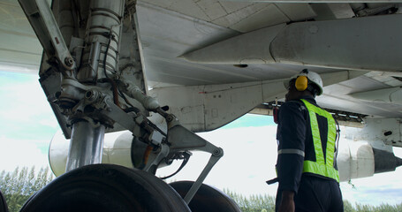 the black male aircraft mechanics use hand tools to work on inspection and do maintenance of an airp