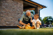 © Dusan Petkovic - Happy granddad and grandson crouching in backyard with a dog and playing with it.