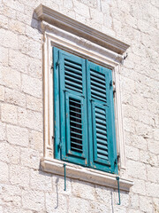 Turquoise wooden shutter on a stone building