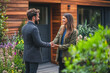 © eshana_blue - Real estate agent is shaking hands with a woman in front of a modern sustainable house, they both look very happy