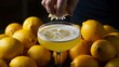 © Kartik - Cropped hand squeezing lemon juice to a glass of see-through foamy yellow cocktail. Lots of lemons. Moody still life. Refreshing drink.
