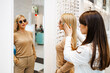 © Dusko - Beautiful and fashionable woman choosing eyeglasses frame in modern optical store. Female seller specialist helps her to make right decision.