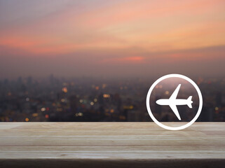 Canvas Print - Airplane icon on wooden table over blur of cityscape on warm light sundown, Business transportation service concept