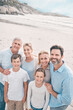 © peopleimages.com - Portrait, smile and summer with big family on beach together for holiday, travel or vacation. Blue sky, hug or love with senior people, parents and sibling children outdoor for bonding or wellness