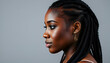 © Tino - A young Black woman with long braided hairstyle, against a gray background