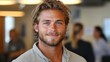 © aicandy - A smiling young man with blond hair and a casual shirt stands in a brightly lit indoor setting with blurred individuals in the background