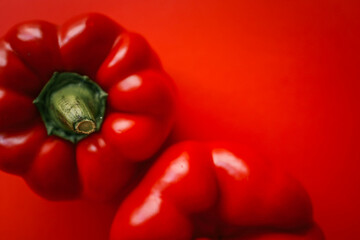 minimalist image featuring two vibrant red bell peppers placed against a matching red background