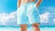 © Vee - A man enjoys summer by showcasing stylish blue swim shorts on a sunny beach, ready for a day of fun and relaxation.