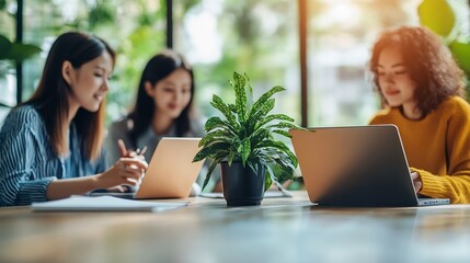 Leinwandbilder - Three people are sitting at a table with a laptop and a tablet They are working together on a project : Generative AI