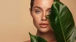 © Irina Ukrainets - A close-up portrait of a woman with striking features. She is partially hidden behind a large green leaf, creating an intriguing contrast with a soft background.