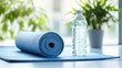 © savittree - Close-up of a yoga mat with a rolled-up towel and water bottle, all set against a clean white background