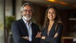 © The Little Hut - Portrait of two smiling mature Latin business man European business woman standing arms crossed isolated on beige background Diverse colleagues group team of confident professional bus : Generative AI