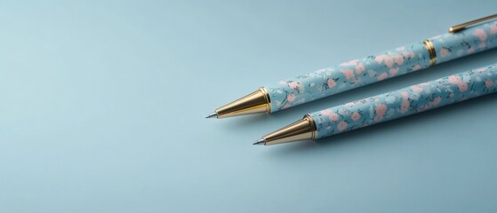 Two pens with a blue and pink design sit on a blue background