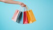 © nadysilence - hand holding shopping bags coming out from the right edge on a light blue background in the right corner of the frame studio light studio photo