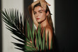 © blackday - Young woman with blonde hair is holding a palm leaf  in sunlight