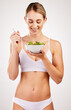 © Nina2024/peopleimages.com - Woman, underwear and salad for diet in studio, healthy nutrition and vegan detox on white background. Female person, eating vegetables and lingerie for organic food for vitamins, meal and minerals