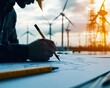 © PrusarooYakk - Engineer designing a renewable energy project with wind turbines and transmission towers in the background, symbolizing innovation and sustainability.