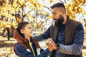 Dad and son bonding in the colorful park. Autumn day.