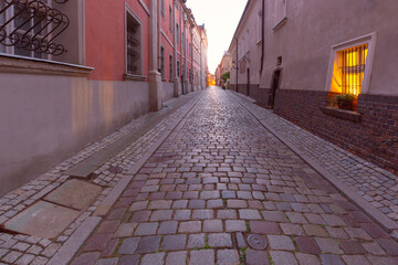 Wall Mural - A deserted narrow cobblestone street in the center of Poznan at dawn.