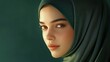 © Mickey - A portrait of a beautiful woman wearing a hijab, with a soft green background. She is looking towards the right, with a thoughtful expression. Her beauty is highlighted by the soft lighting, and the h