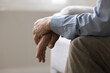 © fizkes - Cropped view, folded hands of unknown senior, man sitting on couch indoors. Close up shot of unrecognizable lonely retired male, deep in thoughts about senile diseases, loneliness in nursing house
