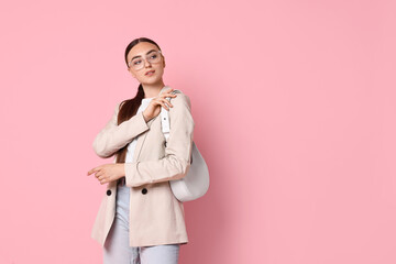 Poster - Stylish woman in beige jacket with bag on pink background, space for text