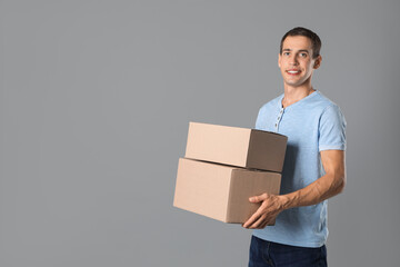 Wall Mural - Moving into new house. Man with cardboard boxes on grey background, space for text