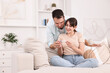 © New Africa - Happy young couple with pregnancy test on sofa at home