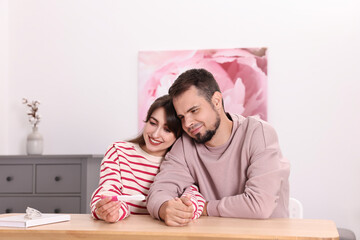 Wall Mural - Happy young couple with pregnancy test at wooden table indoors