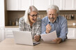 © fizkes - Happy aged couple read letter, hold document, bank statement, feels excited by great news, receive notice of loan repayment, money back, gesturing with joy. Celebrate financial success, pension growth