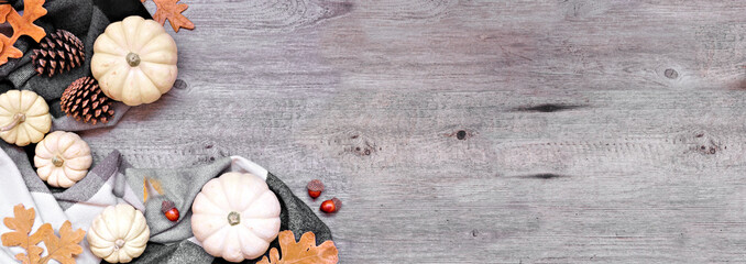 Poster - Cozy autumn corner border with blanket, white pumpkins, leaves and natural decor. Above view over a grey wood banner background. Black, white and brown theme.