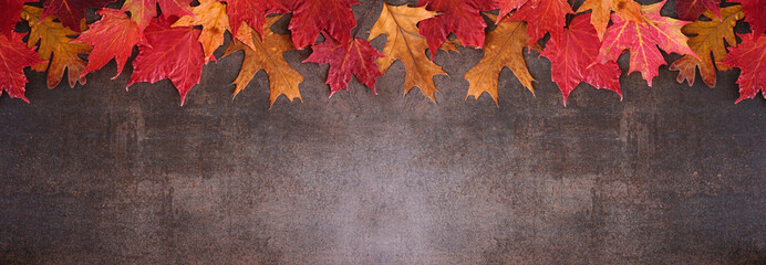 Aufkleber - Colorful autumn leaves top border over a dark stone banner background. Overhead view with copy space.