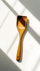 Minimalist Wooden Spatula Poised on Crisp White Surface with Dramatic Shadows