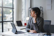 © amnaj - Businesswoman is holding a pen and thinking about new business strategies while working on a tablet in the office