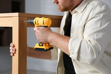 Sticker - Man with electric screwdriver assembling table indoors, closeup