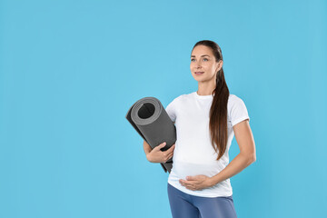 Poster - Beautiful pregnant woman with exercise mat on light blue background