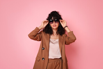 Wall Mural - Beautiful young woman in stylish suit and sunglasses on pink background