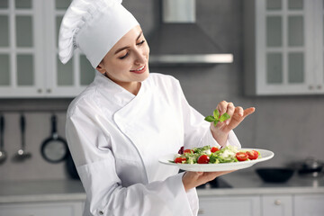 Wall Mural - Professional chef decorating delicious salad with basil in kitchen