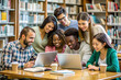 © Butsarakham - A group of people are sitting around a table in a library, looking at a laptop. They are all smiling and seem to be enjoying themselves. The atmosphere is friendly and relaxed