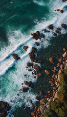 Wall Mural - Aerial view of ocean waves crashing against rocky coastline, showcasing vibrant turquoise waters and white foam. The natural patterns of the waves create a dynamic and serene seascape.