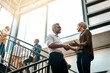 © SometimesNever/peopleimages.com - Employees, handshake and office with greeting on stairs for business deal and opportunity. People, thank you and welcome with partnership, support and agreement for teamwork, collaboration and smile