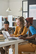 © Mediaphotos - Smiling students using digital tablet while studying together at table during class in school or college