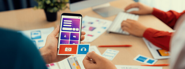 Panorama banner of startup UX developer or company employee design user interface or UI prototype for mobile application or website software with software display on smartphone in office. Synergic