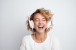 © cato_rium - Curly European young woman wearing headphones smiling happily on a white background. Design for advertising headphones, streaming services, and electronics stores. Banner template with place for text