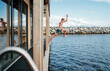© Soloviova Liudmyla - Jumping teen boy into the cold Fjord water from Scandinavian floating sauna deck. He shining with happiness and relaxation perfectly capturing serene and invigorating sauna experience