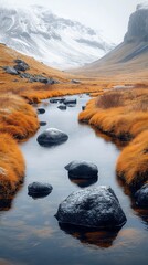 Wall Mural - Tranquil stream flows through an autumn landscape with snow-dusted mountains in the background and rocks scattered in the water