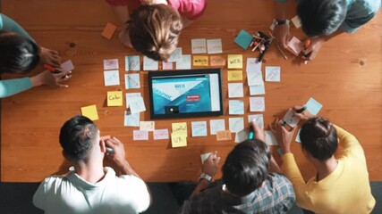 Top down view of programmer brainstorming and planning about web design while looking at tablet wireframe prototype. Aerial view of skilled developer team talking about digital application. Symposium.