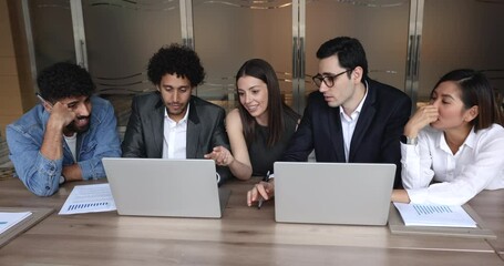 Wall Mural - Happy diverse business team discussing online content at laptop, watching project video presentation. Arab developer showing application, software, service on computer to multiethnic employees