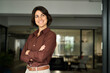 © insta_photos - Happy confident young Hispanic professional business woman standing at work in office arms crossed looking away, proud businesswoman leader executive thinking of future career success.