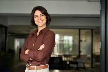 happy confident young hispanic professional business woman standing at work in office arms crossed l